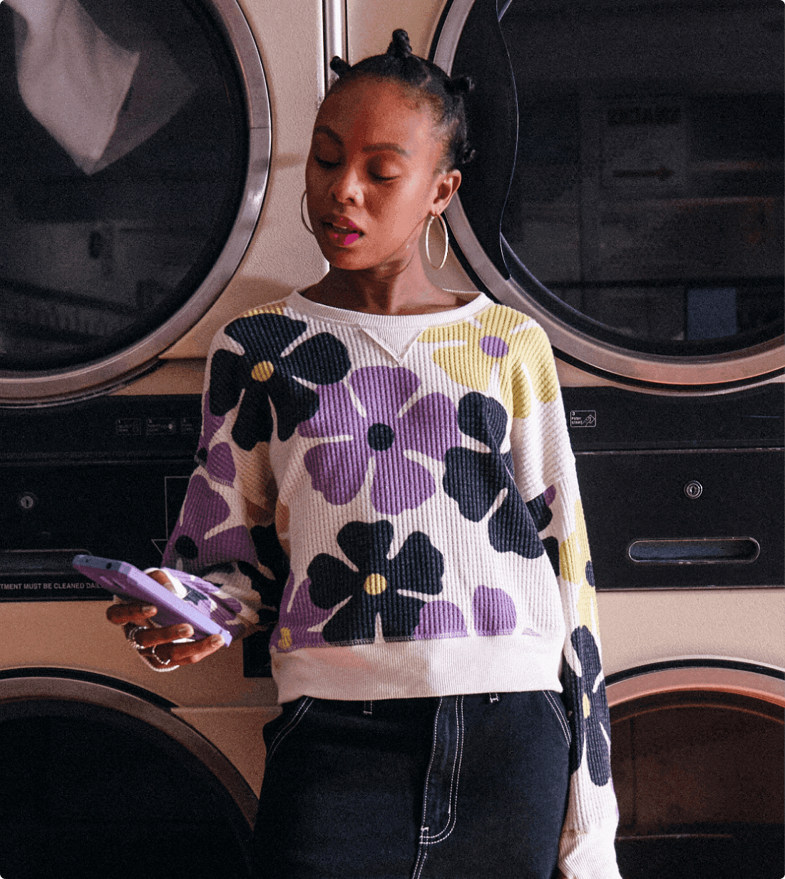 woman at laundromat with colorful shirt and phone in purple case