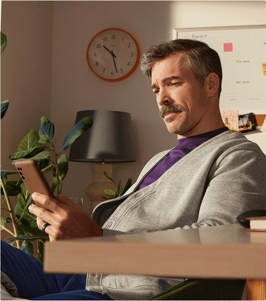 man sitting at desk reviewing message on phone